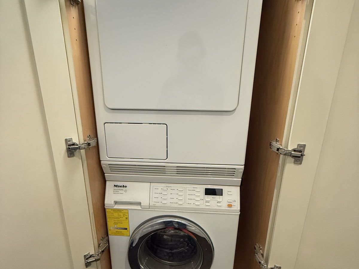 Miele washer-dryer stacked pair in a hallway closet