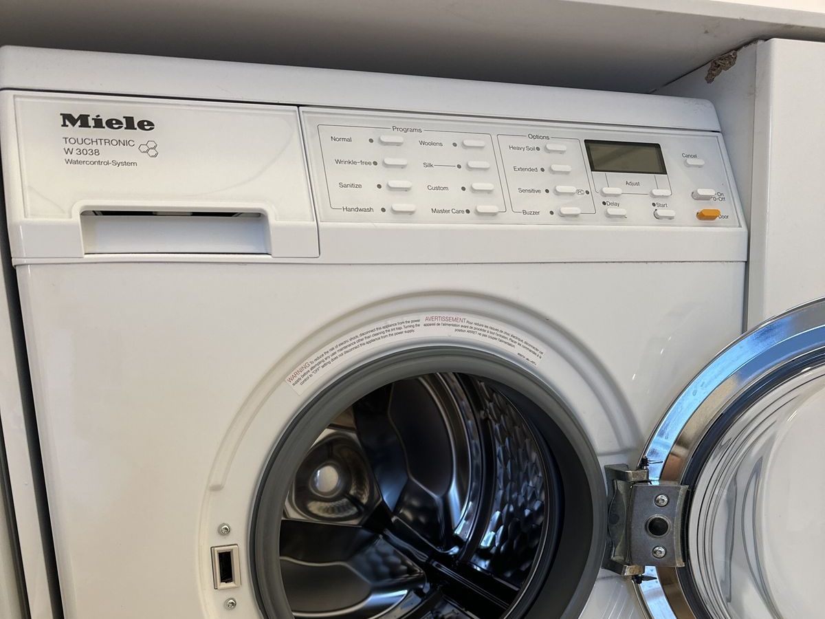 Miele compact washer with the door open in a NYC apartment