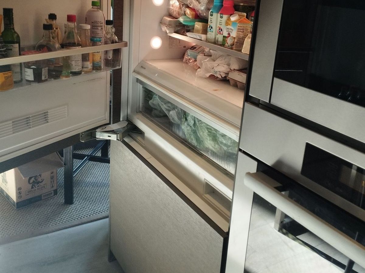 Miele built-in refrigerator with open freezer drawer next to wall ovens