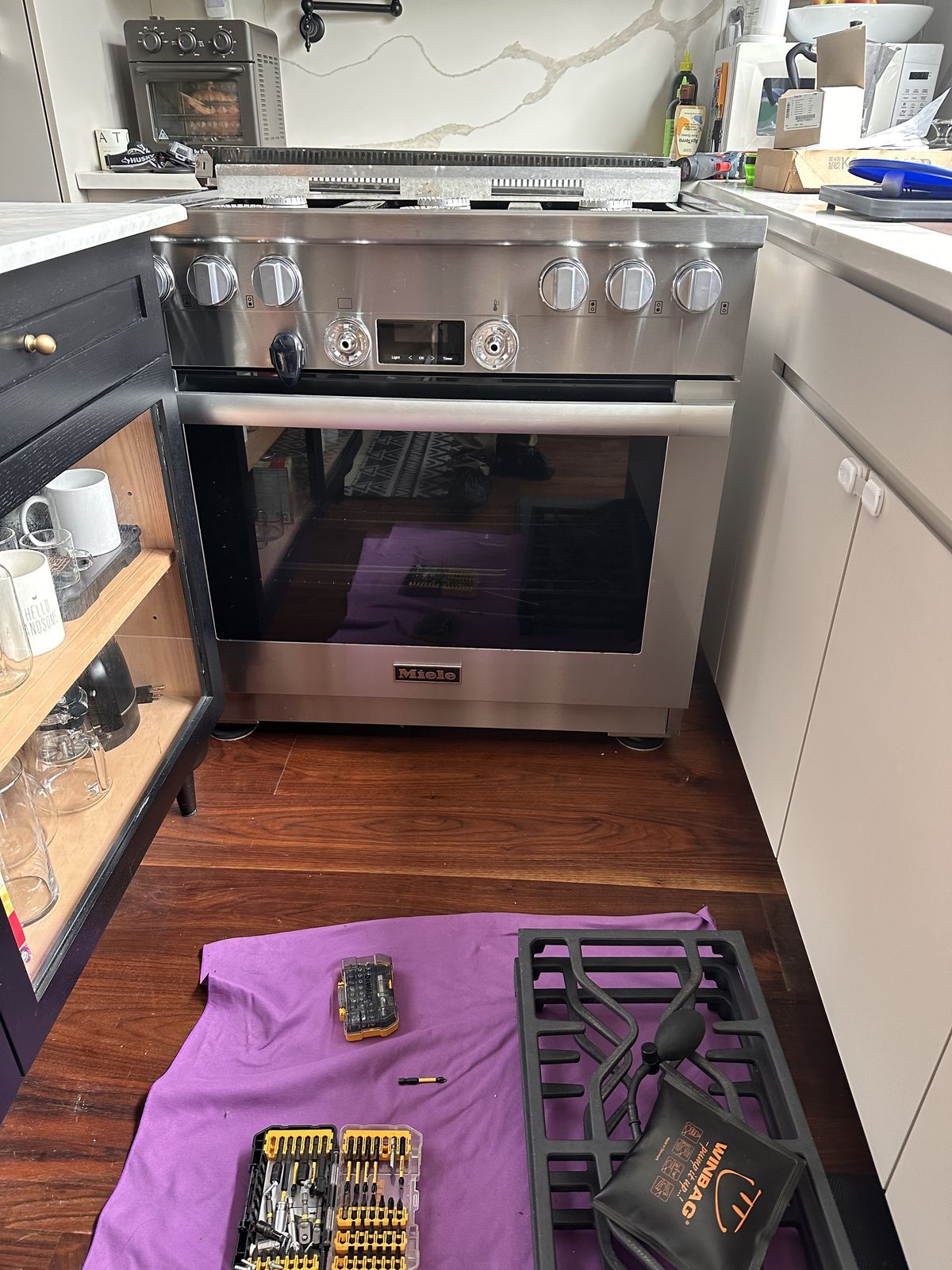 Miele range mid-repair in an NYC kitchen with grates removed and tools laid out