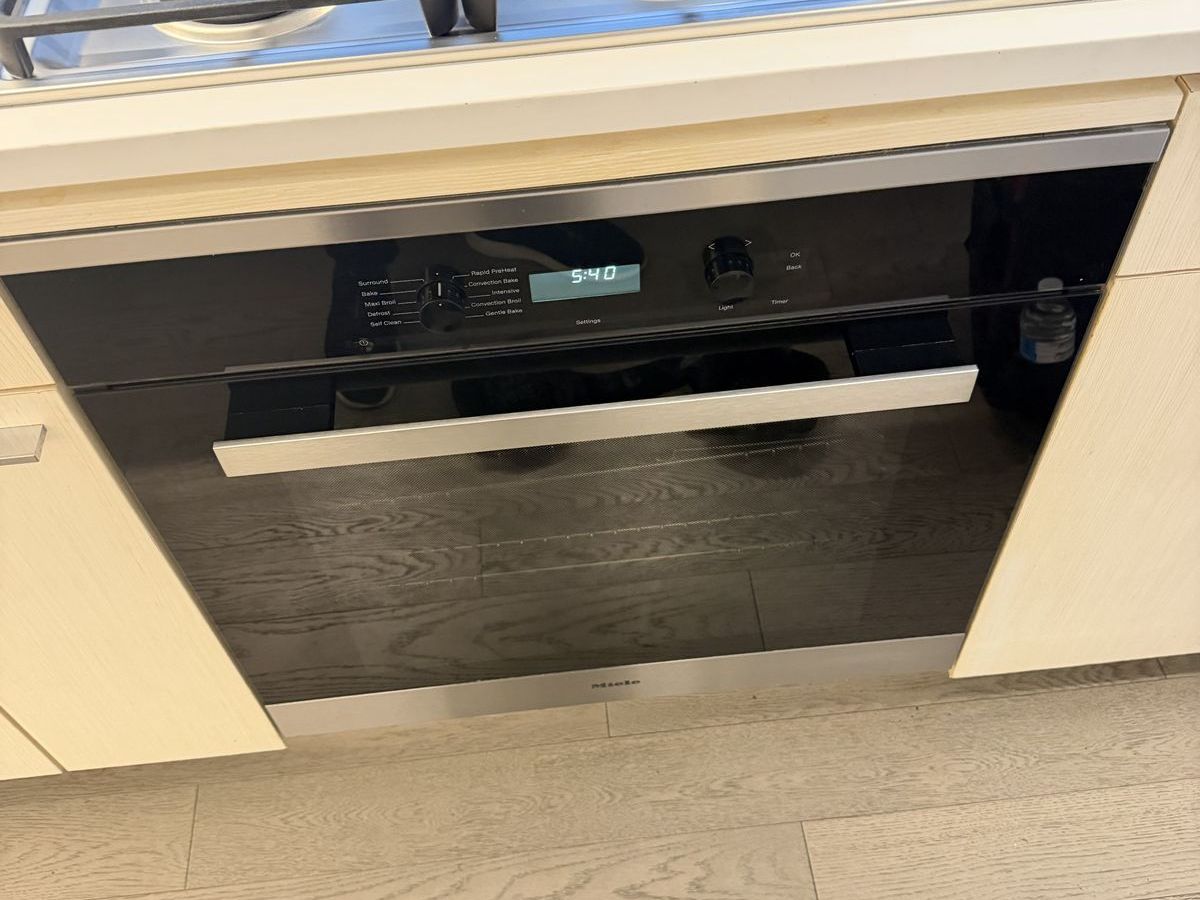Built-in Miele H-series oven door and control panel under a gas cooktop