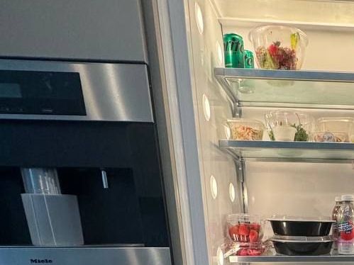 Miele built-in coffee machine beside a refrigerator column in an NYC kitchen