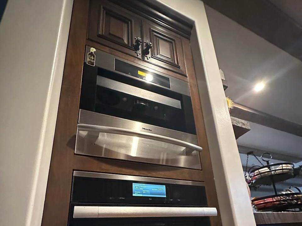 Miele CVA coffee machine built into dark wood cabinetry above a warming drawer