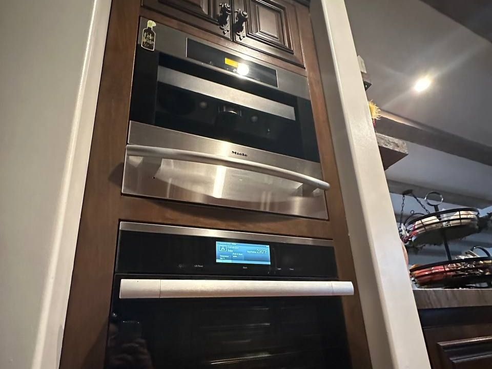 Miele coffee machine and warming drawer built into a dark wood column in NYC