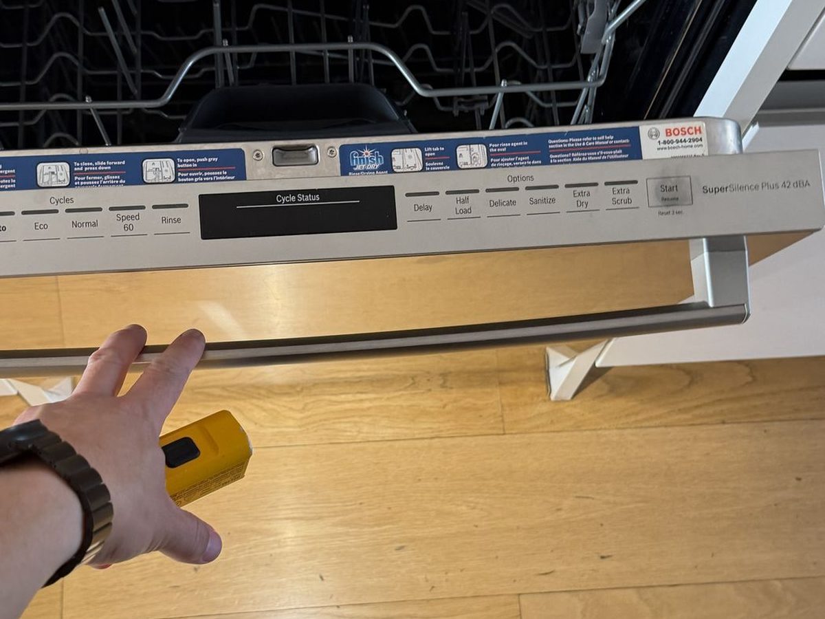 Technician checking an open Bosch dishwasher control panel