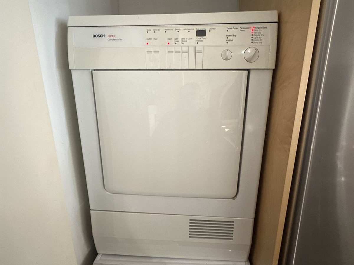 Bosch dryer in a narrow NYC laundry closet next to the refrigerator