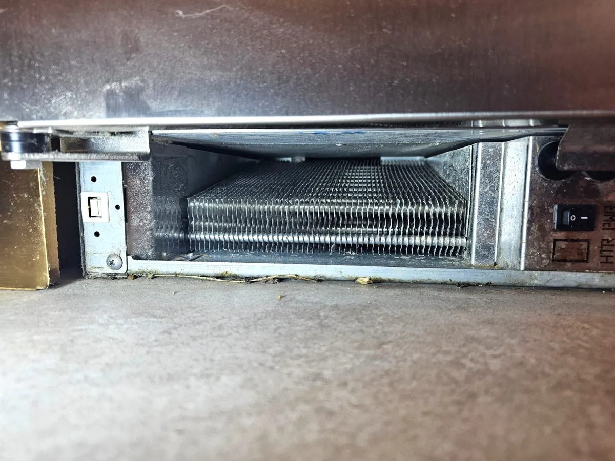 Bottom compartment of a built-in Sub-Zero with the coil behind the kickplate grille