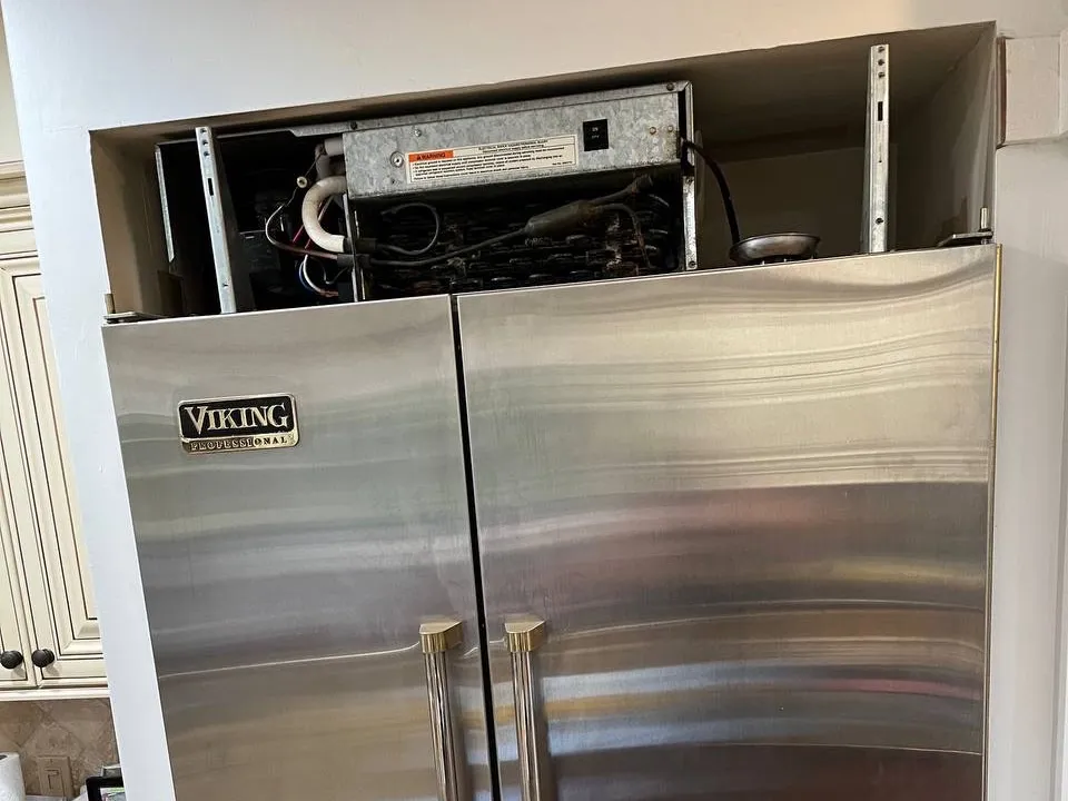 Viking built-in refrigerator with the top compressor compartment open for service