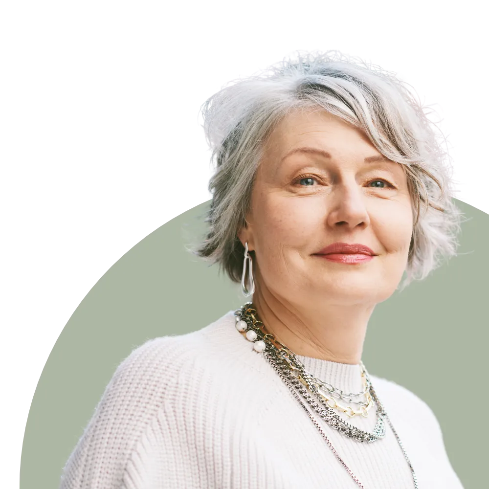 A picture of a middle aged white haired lady smiling on a circular background.