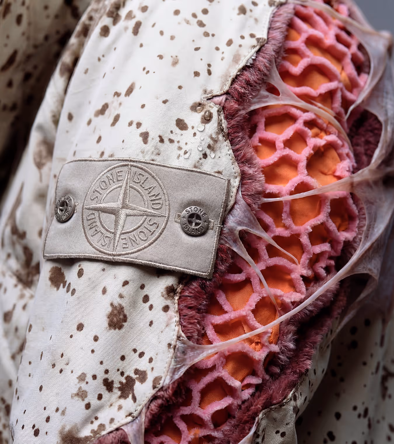 A jacket with pink organic material and stone island logo