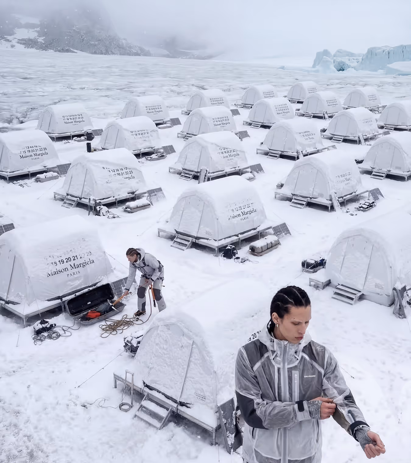 Salomon and Maison Margiela white tents and two people setting up camp on ice covered land.