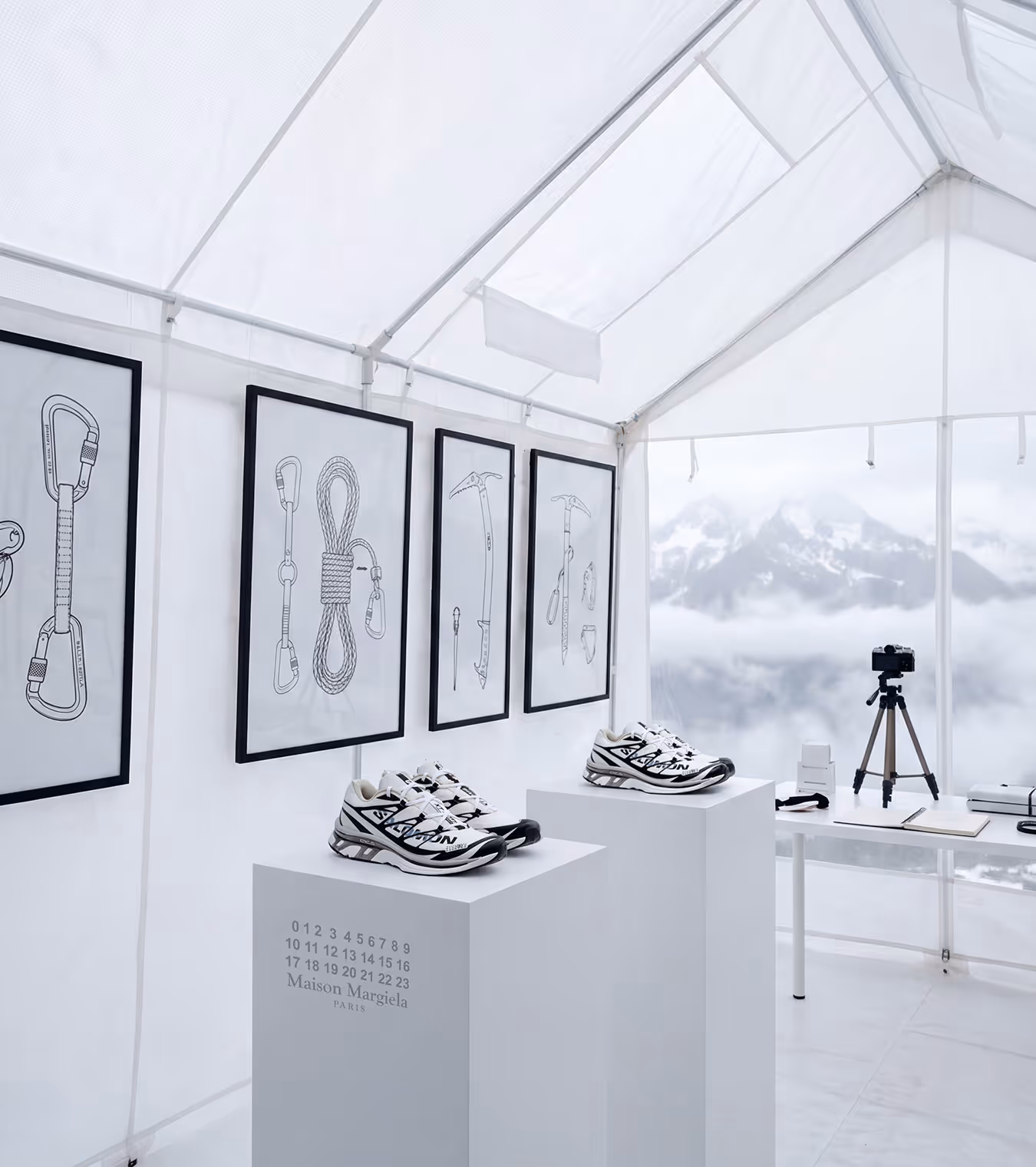 Salomon and Maison Margiela sneakers displayed on a mountain in a tent in a snow covered region. 