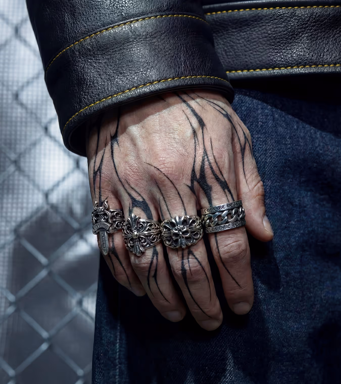 A tattooed hand with Chrome Hearts rings.