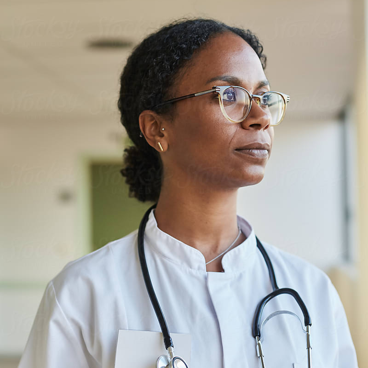 Black female physician looking out the window optimistically.