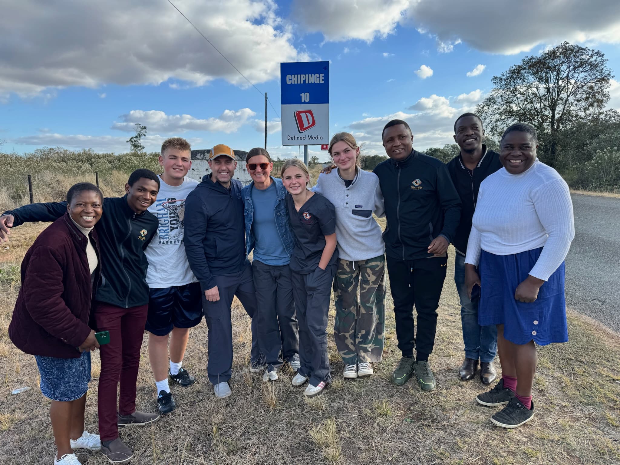 Volunteer team in front of a sign with a group of locals