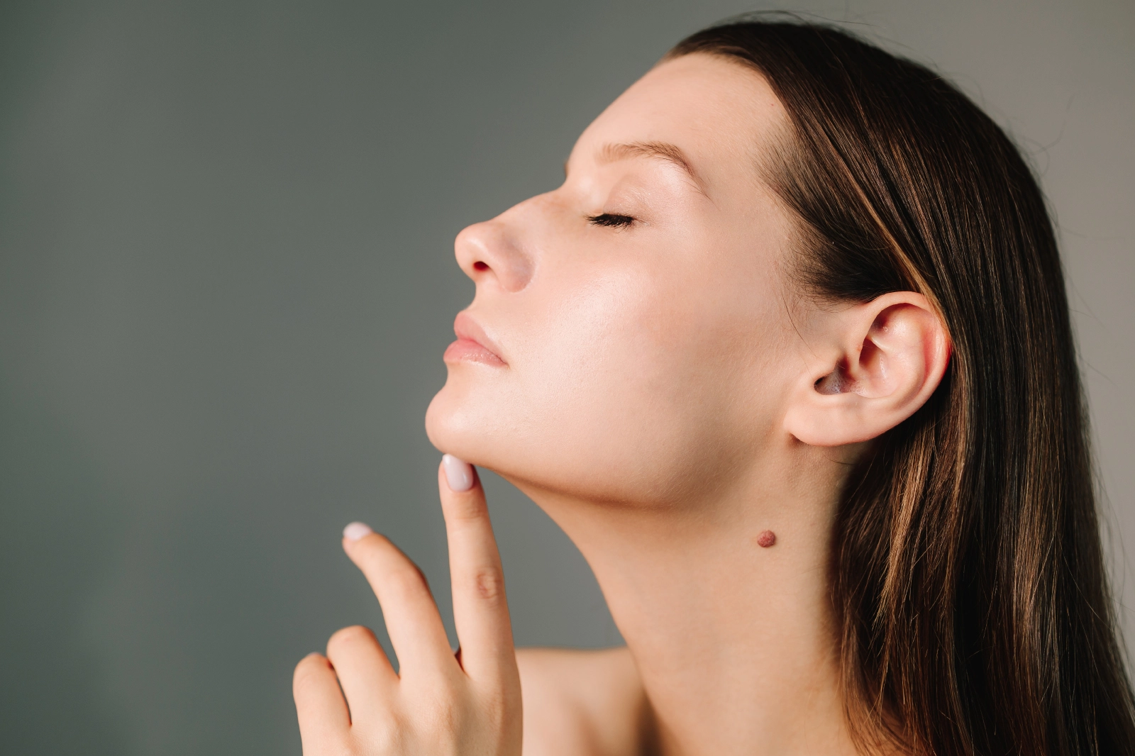 Side profile of a woman touching her chin to highlight her jawline.