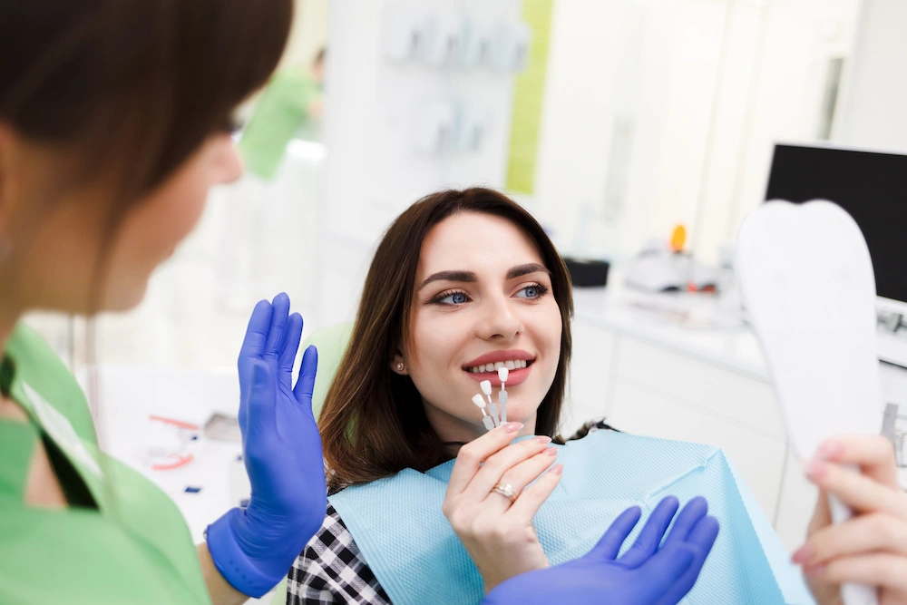 Patient checking tooth shade with a guide and mirror at Coastal Virginia Oral Surgery.