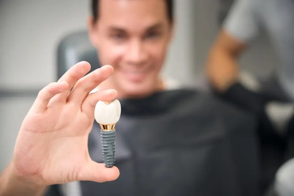 Man holding a dental implant model during a dental appointment.