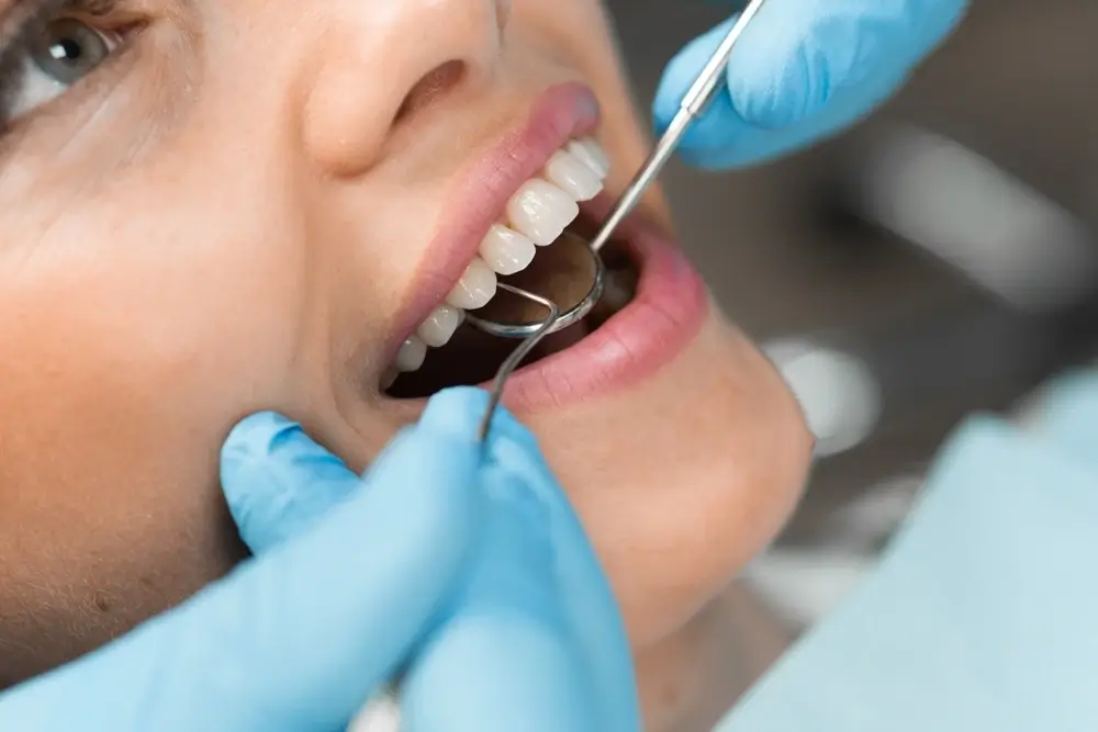 Dentist examining a patient's teeth using a dental mirror and probe.
