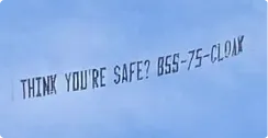 Sky banner with text 'THINK YOU'RE SAFE? 855-75-CLOAK' flying against a blue sky.