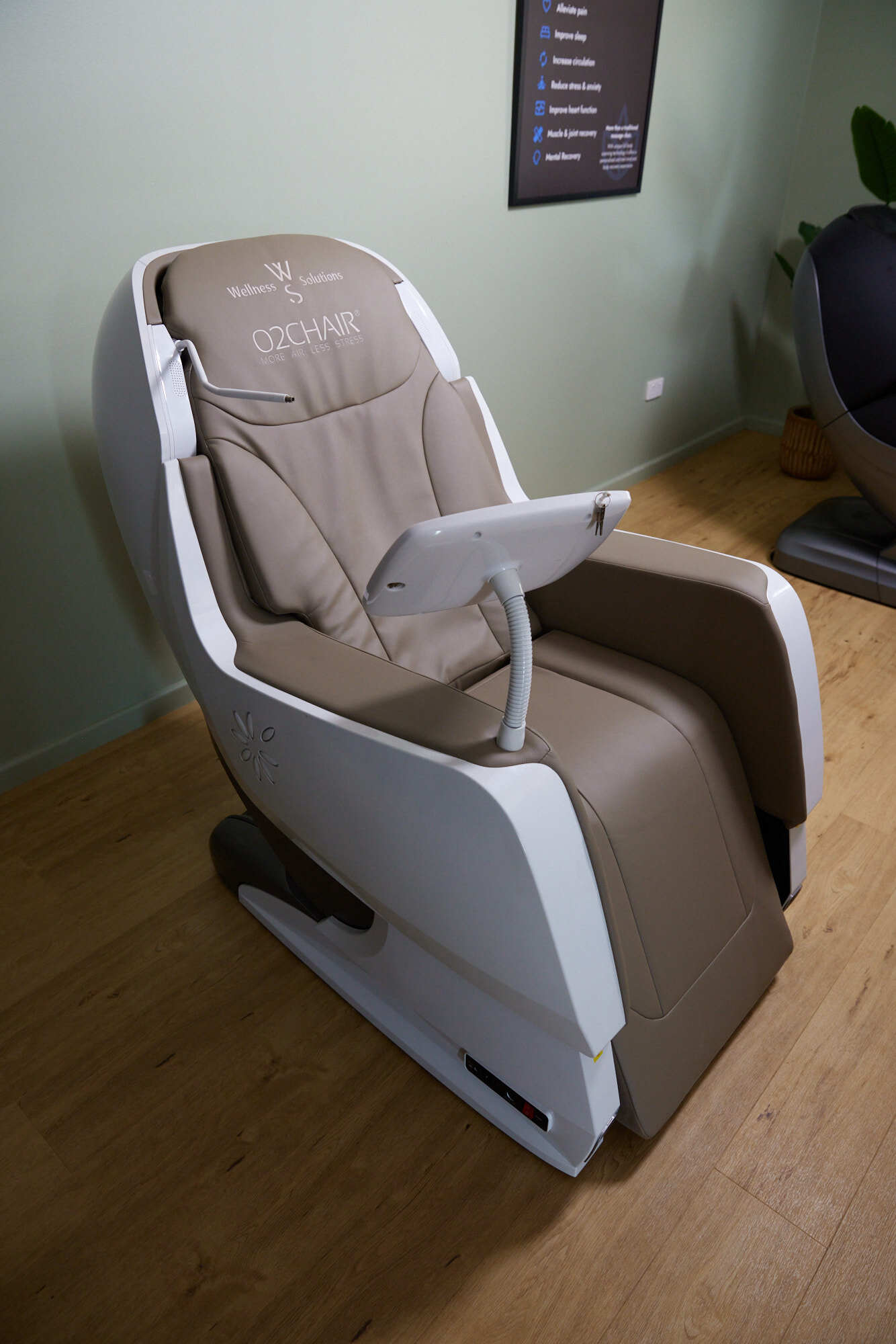 Modern O2Chair by Wellness Solutions with beige cushioned seat, attached tablet, and armrests in a room with wooden floor.