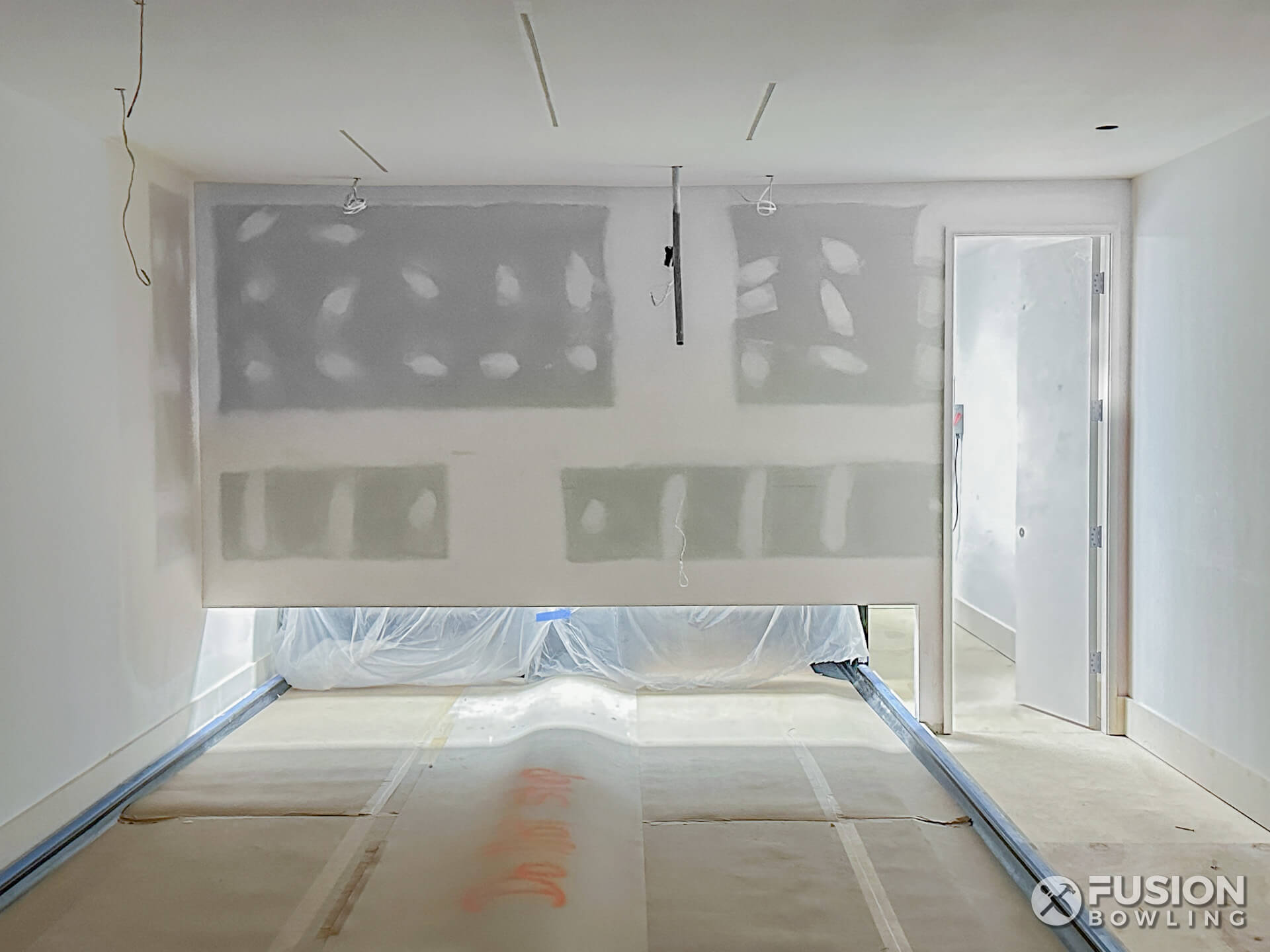 Construction of a curtain wall over a residential bowling alley with lanes protected while being built.
