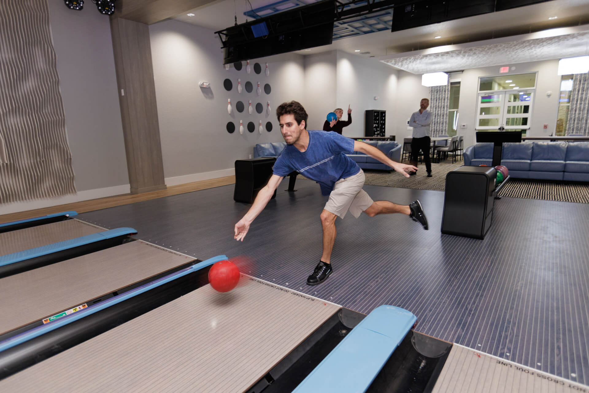 A guy bowling on a bowling lane with a different colored approach.