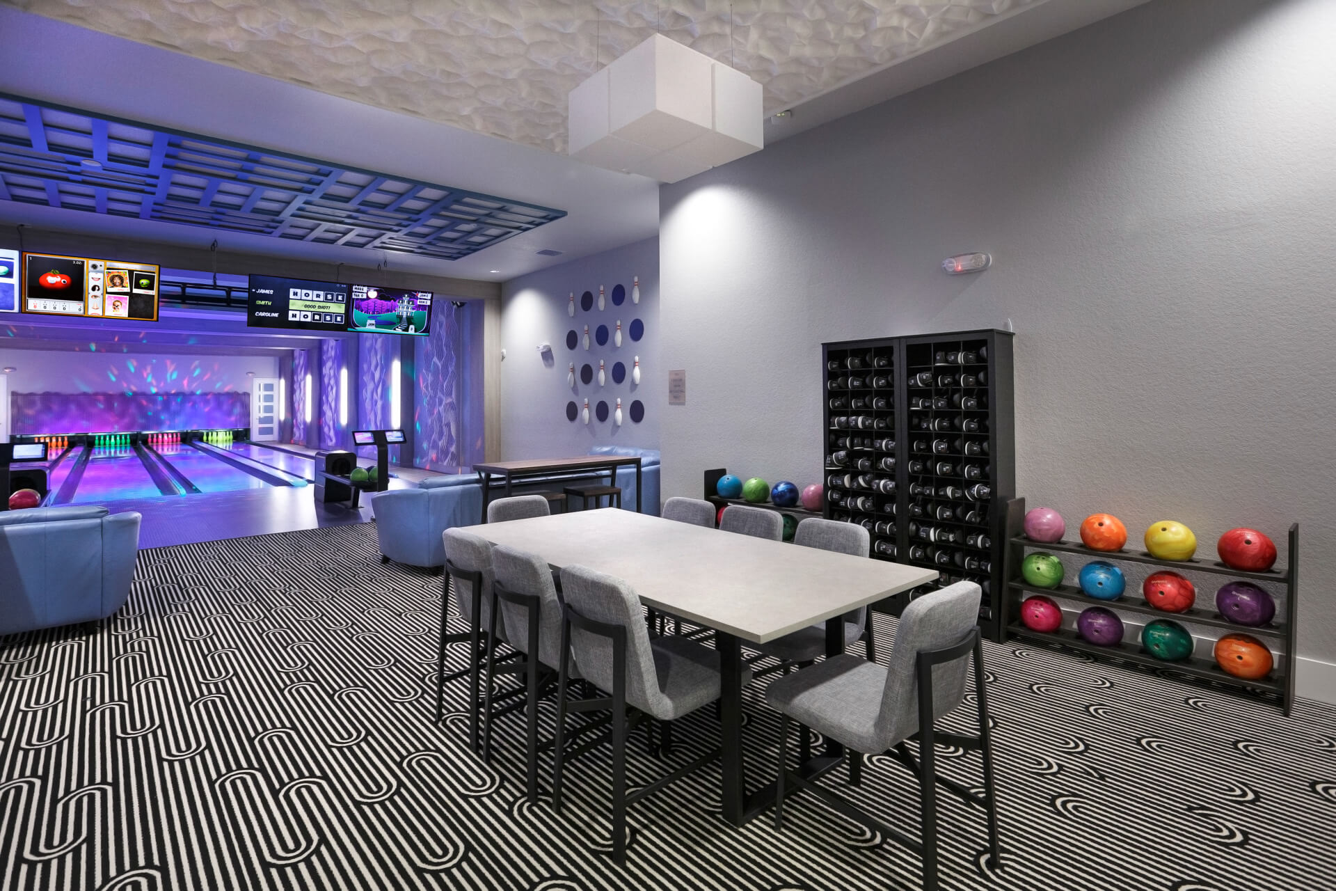Table, chairs, and sofas behind a private apartment complex bowling alley amenity with four lanes in Orlando, Florida by Fusion Bowling.