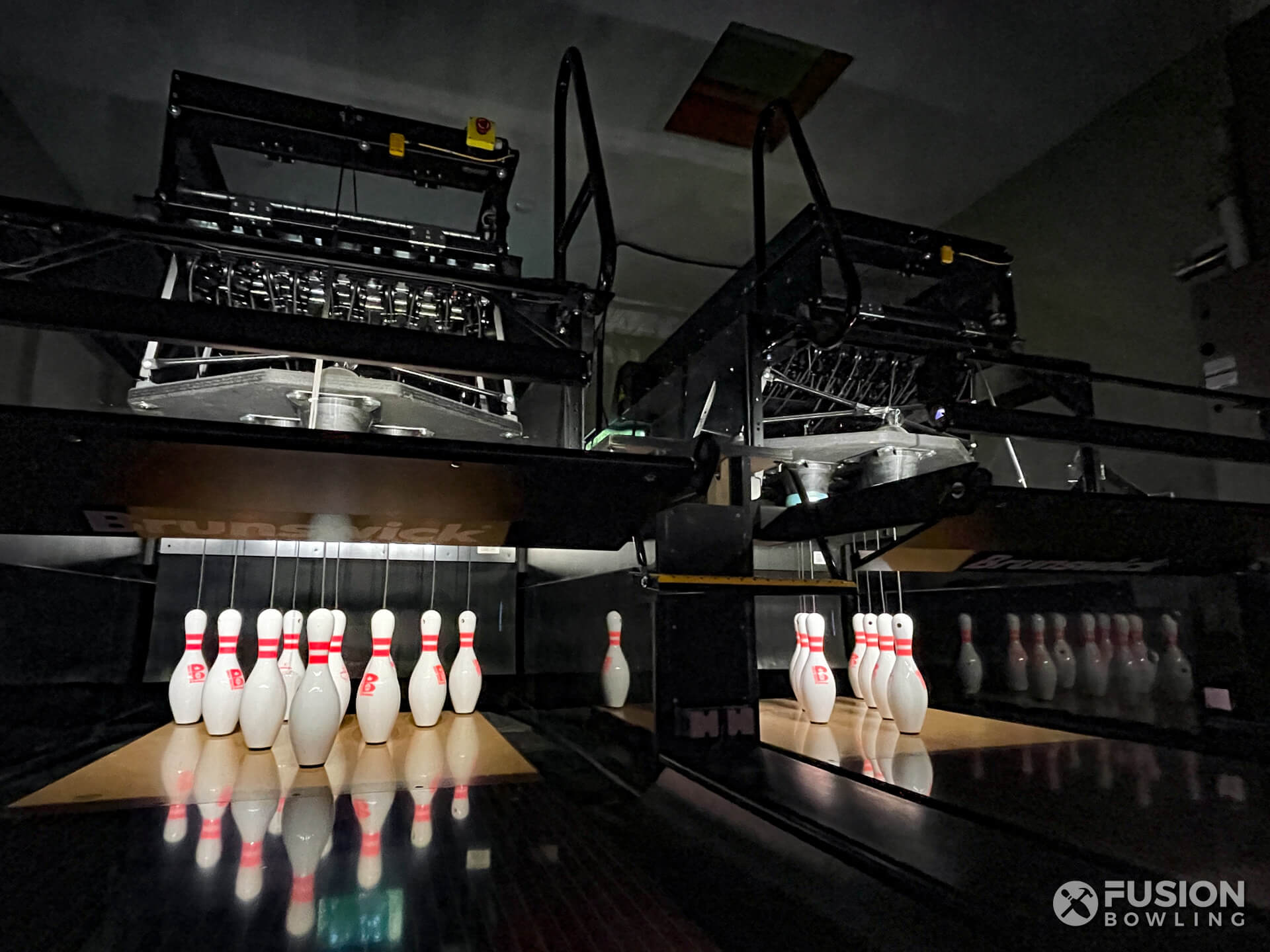 Brunswick pinsetter machines with lit up pins in a dark room.
