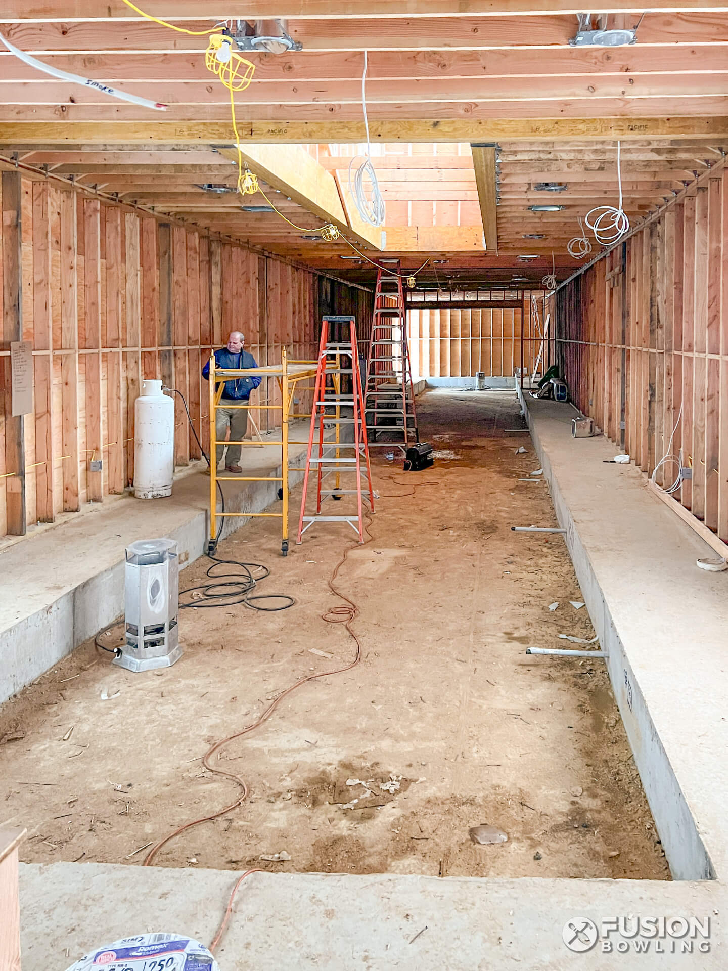Home under construction with a concrete slab depression for a bowling alley.