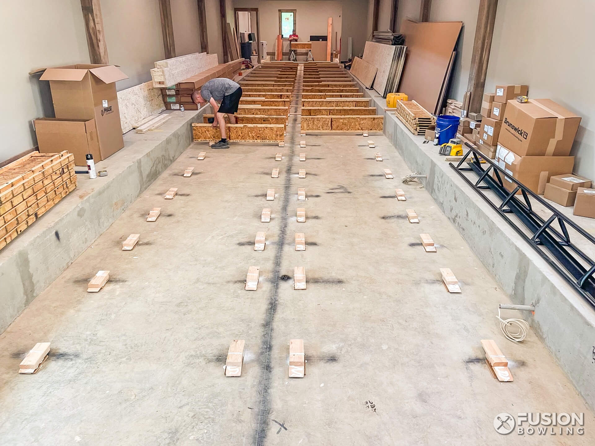 Bowling alley installers lay out the foundation for an indoor in-home bowling lane system.