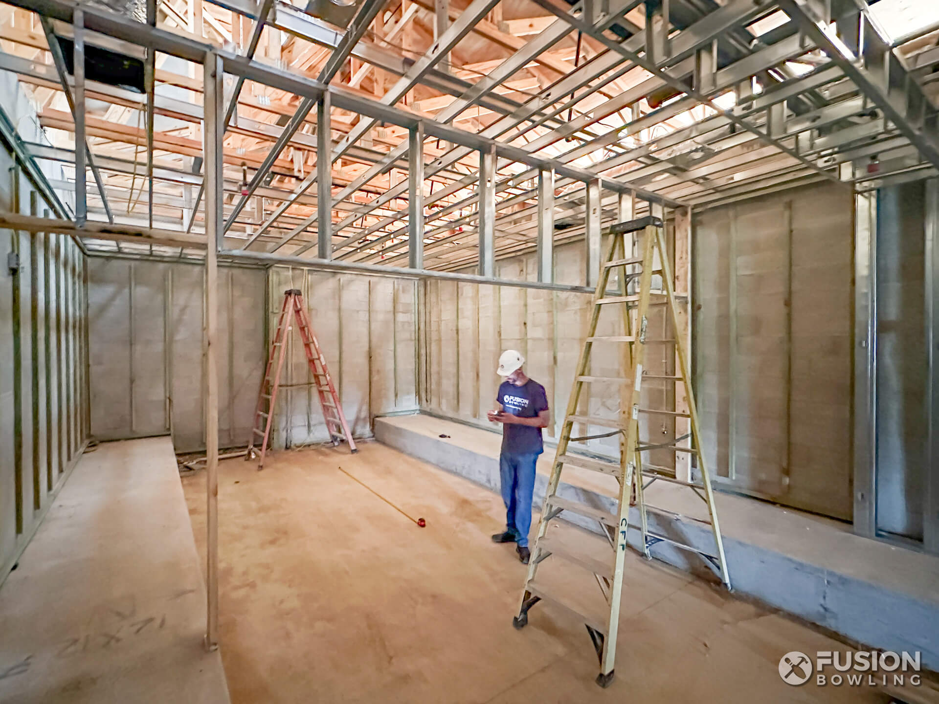 Bowling alley builder standing a concrete foundation depression.
