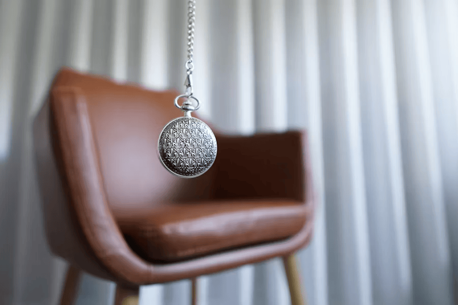 Stuhl im Hintergrund, Hypnoseanhänger im Vordergrund, stellt eine Hypnosetherapie/ Psychotherapie Praxis dar.