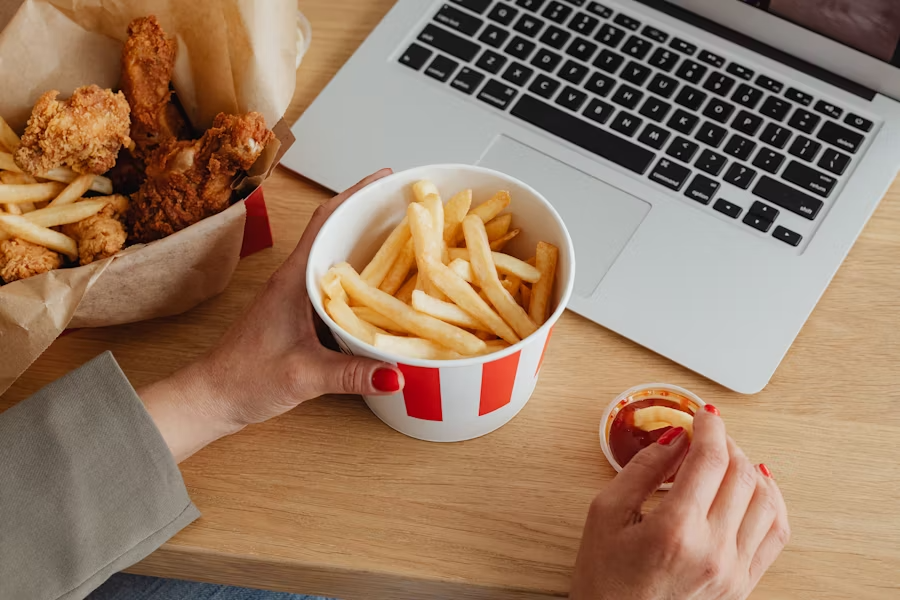 Ungesunde Gerichte werden ohne Besteck am Laptop gegessen.