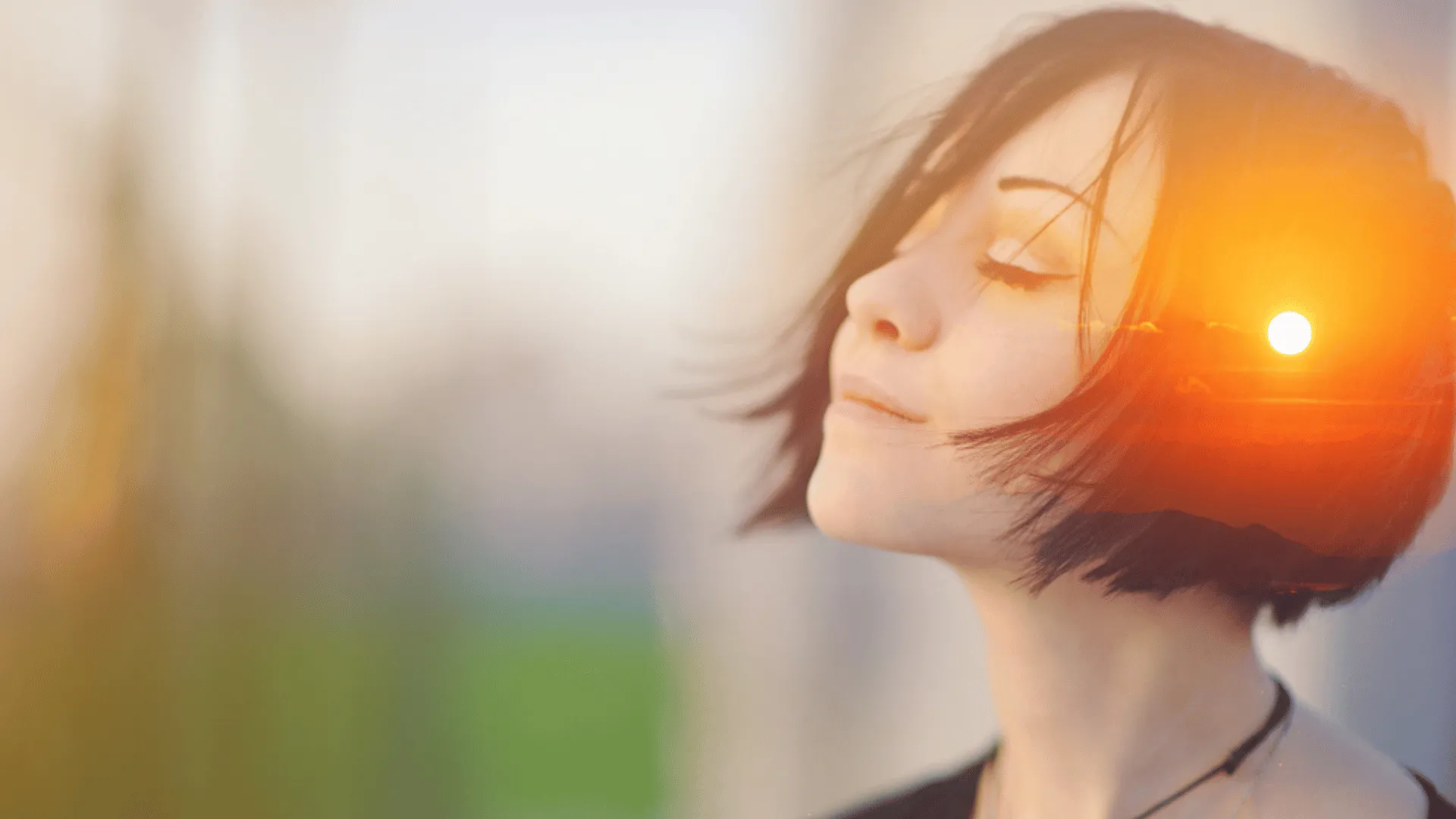 A woman closes her eyes and looks up slightly. She's breathing in deeply and smiling with her mouth closed.