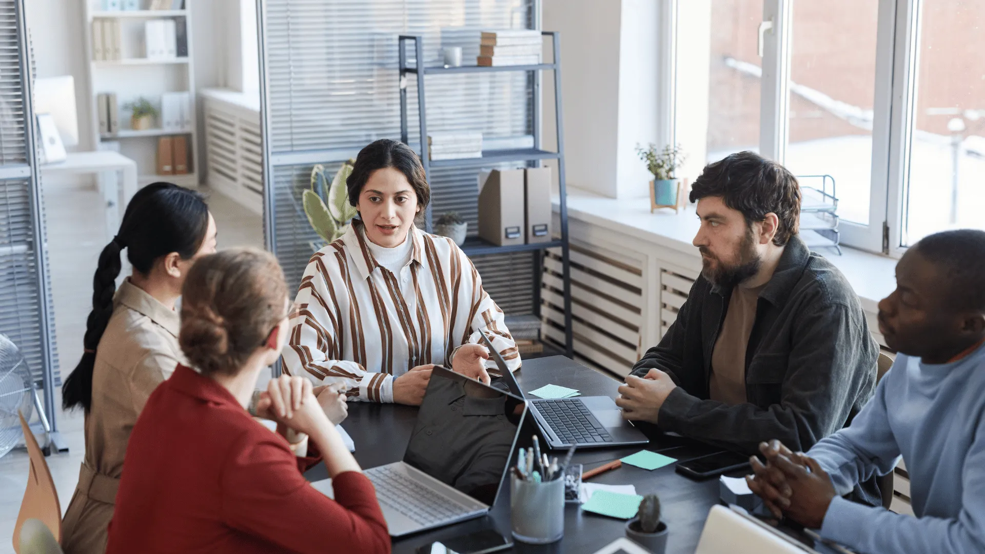 A diverse group of colleagues are sitting around a table discussing a topic.
