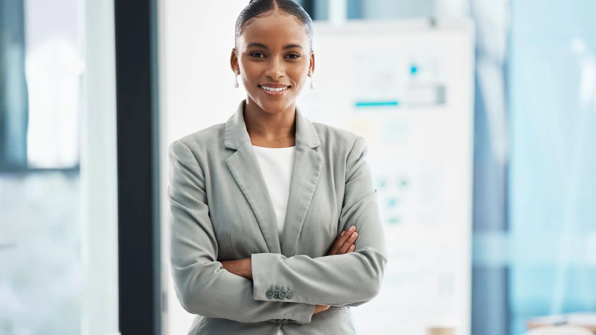 A woman in business attire stands with her arms crossed, exuding confidence as she looks directly into the camera. This image encapsulates the essence of corporate training on leadership, highlighting qualities such as self-assurance, determination, and the ability to command attention. Her direct gaze and confident posture symbolize the strength and assertiveness required in effective leadership, embodying the key attributes that are often developed and refined in leadership training programs within a corporate setting.