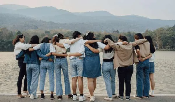 A group of people, with their backs to us, link arms and look at the vista.