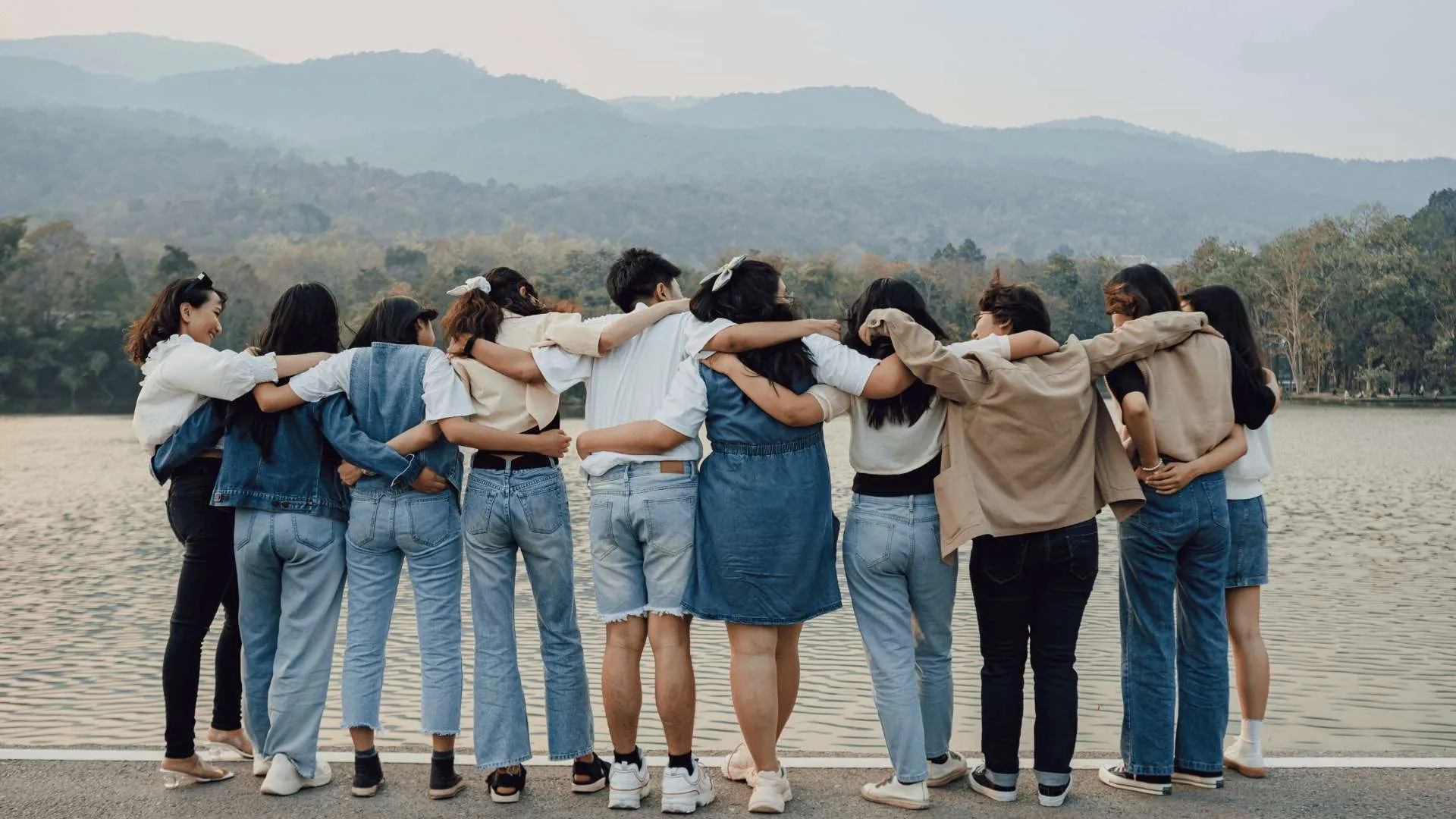 A group of people, with their backs to us, link arms and look at the vista.