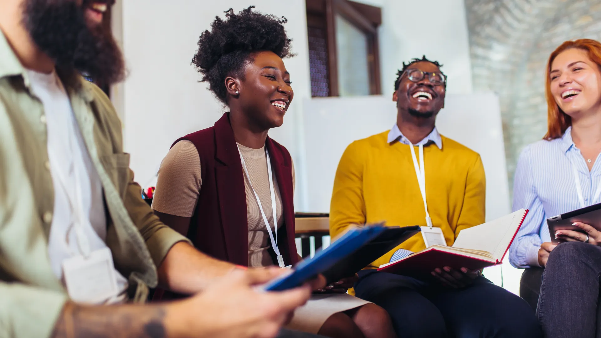 A team of diverse people are sitting in a circle and laughing.