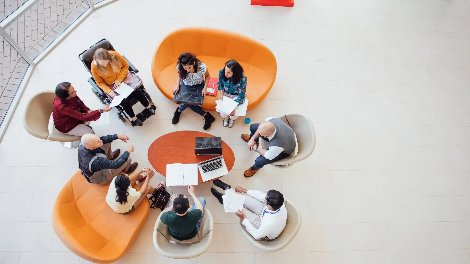 We are looking down from overhead at a diverse group of employees having a discussion in a sitting area.