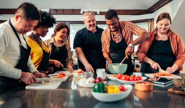 A diverse team of people are taking a cooking class together.