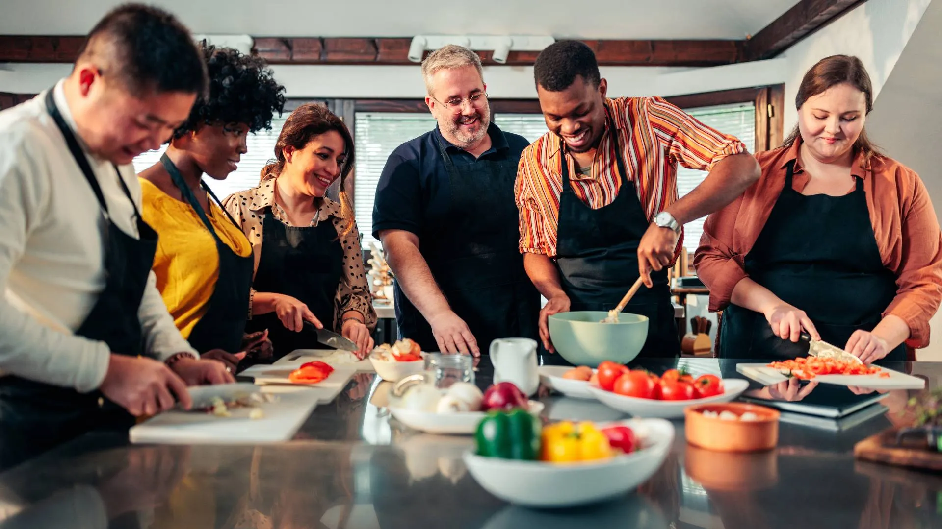 A diverse team of people are taking a cooking class together.