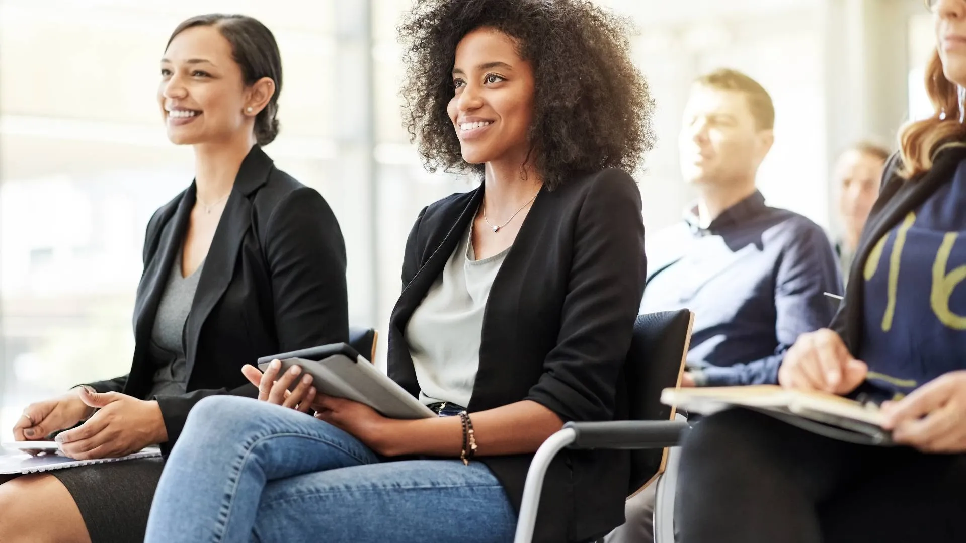 A group of professionals are sitting in a classroom-style training environment.