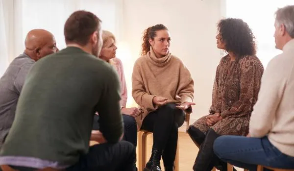 A group of people are sitting in a circle, talking and sharing.