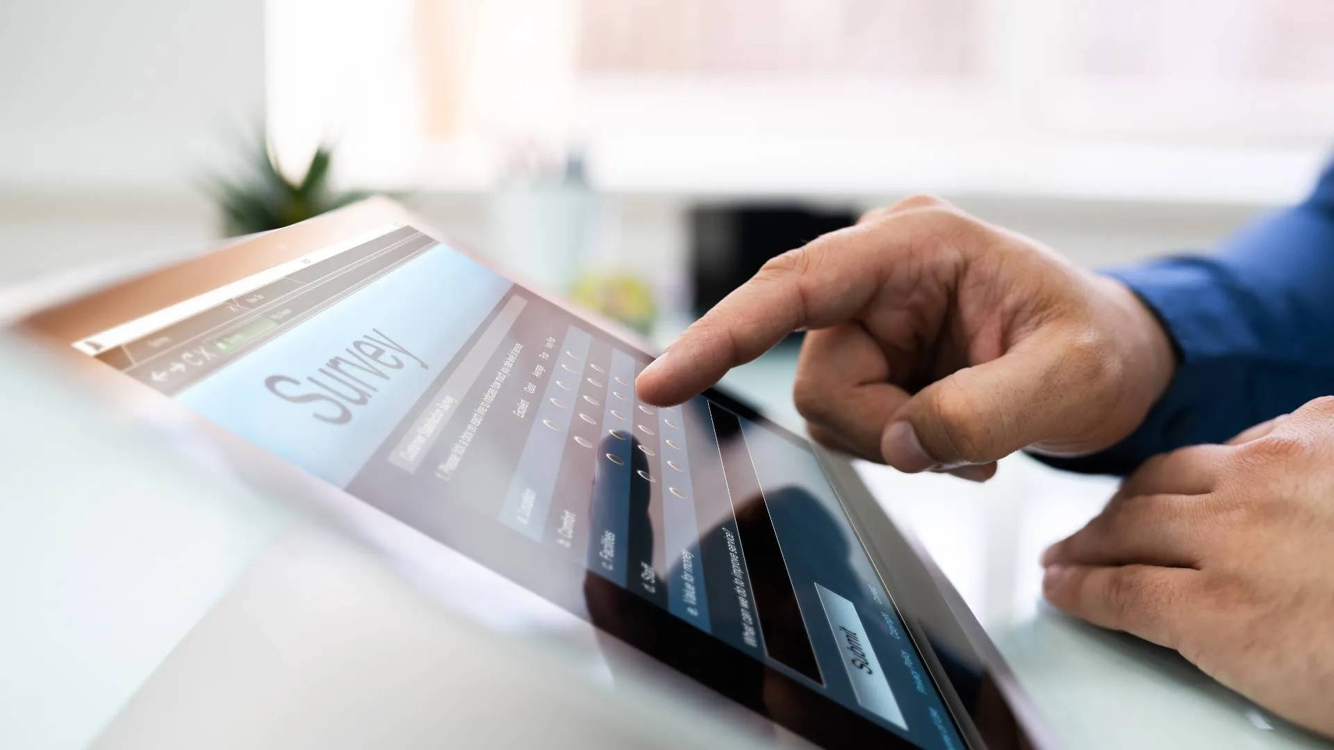 A man's finger is pointing at a screen that reads "Survey".