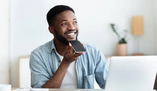 A young man is holding his phone up to his face as he uses its AI tool.