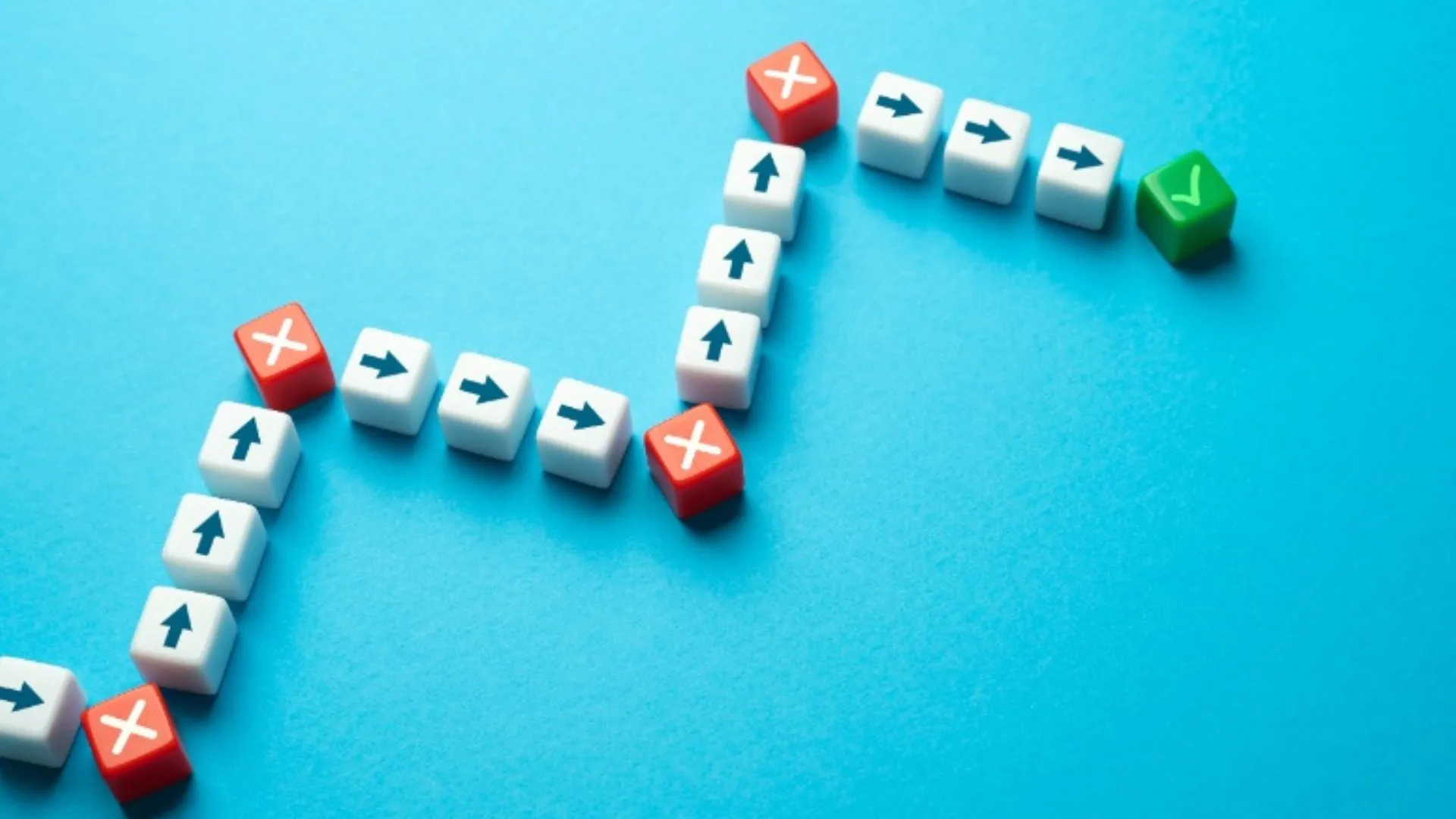 White cubes with arrows and red Xs leading to a green checkmark on a blue background, symbolizing decision-making and how to persevere through challenges.