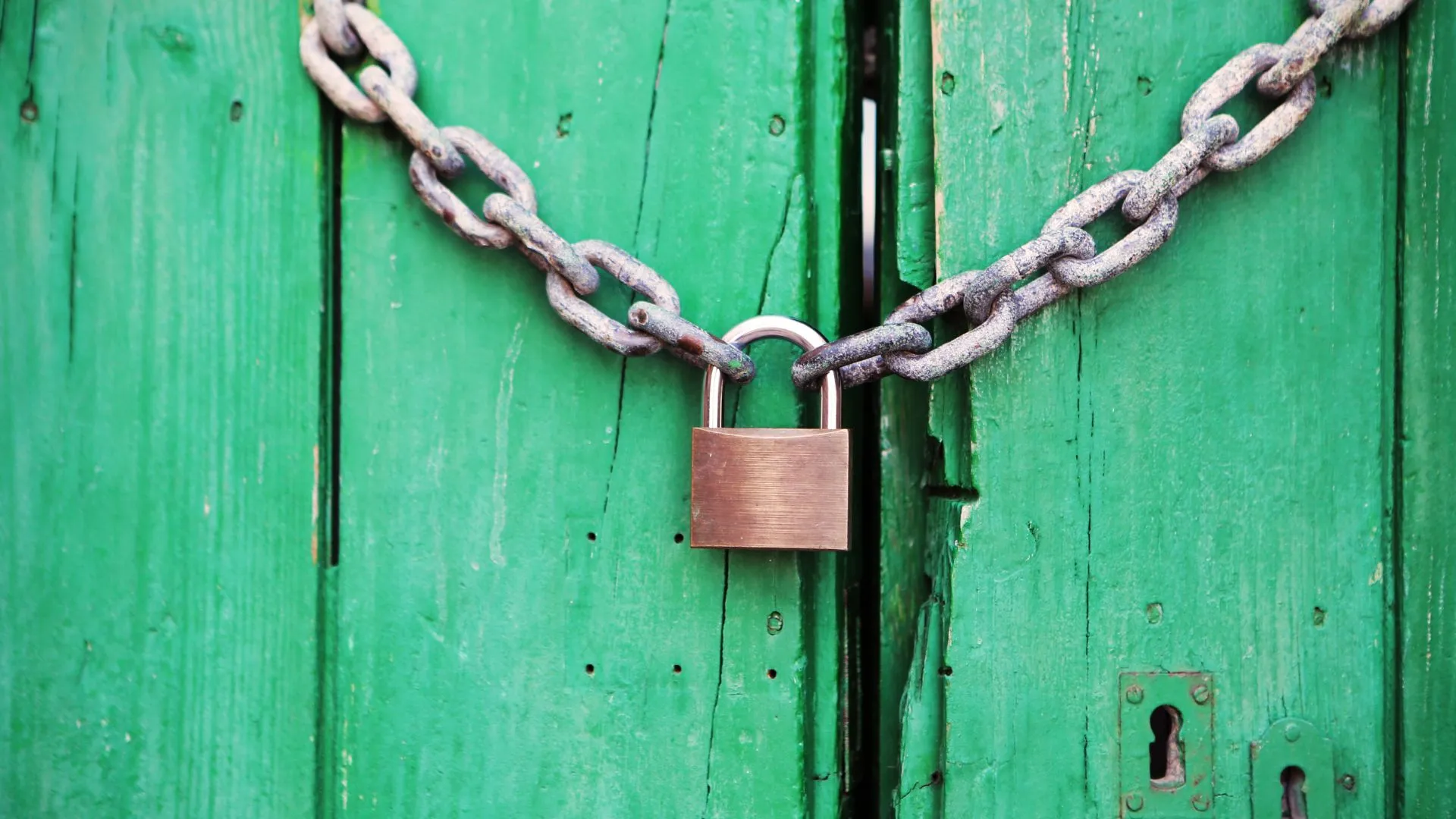 A sturdy chain with a padlock securing a green wooden door, symbolizing building unstoppable alliances through AI training.