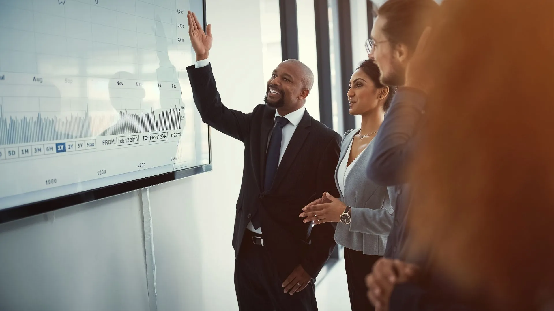 A man is pointing to a presentation, explaining it to his colleagues.